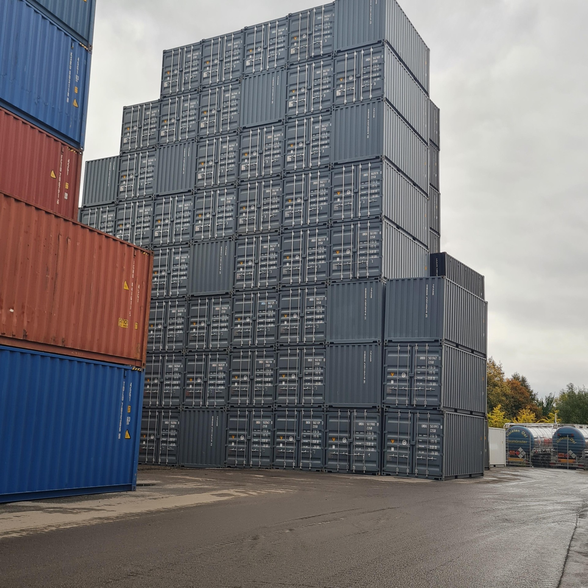 Gestapelte Seecontainer von Neubach Container auf Lagerplatz – Großbestand in Dunkelblau, Rot und Blau