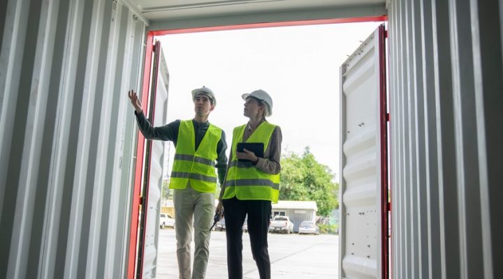 2 Mitarbeiter begutachten Container und Fundament vor der Aufstellung